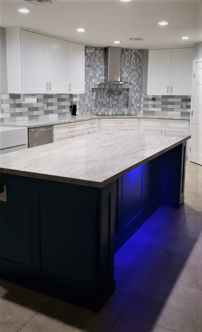 A kitchen with a large island and blue lights.