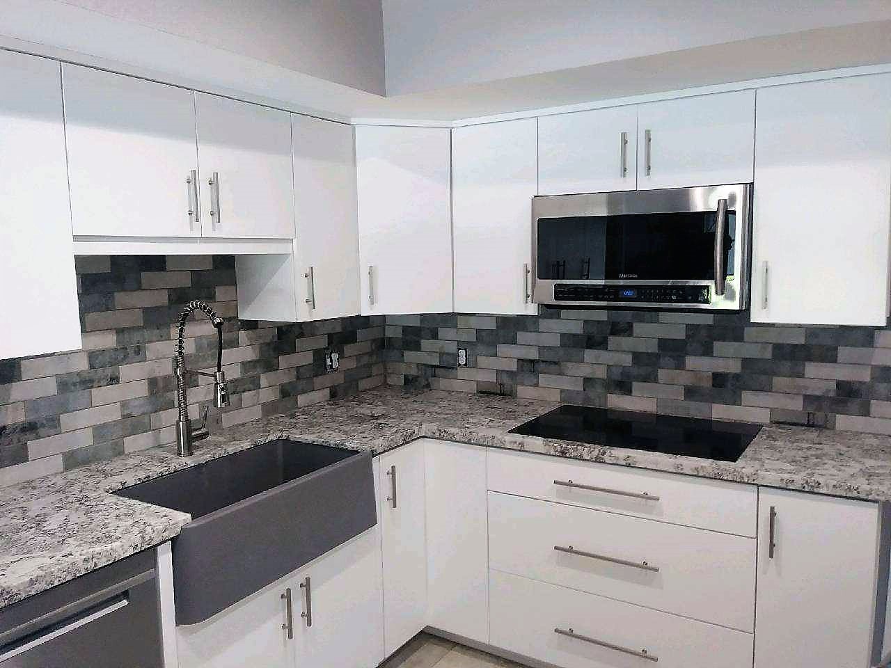 A kitchen with white cabinets and black tile