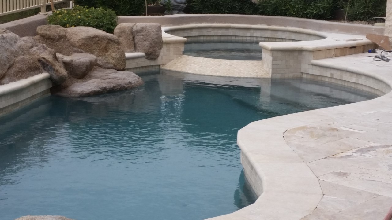 A pool with a stone fountain and steps.